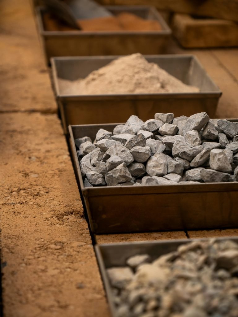 Various construction materials including rocks, and sand in storage boxes.